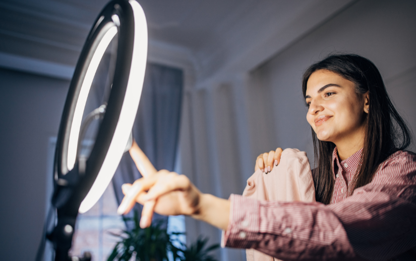 Smiling micro-influencer using a ring light while creating content, showcasing online business tools for entrepreneurs.